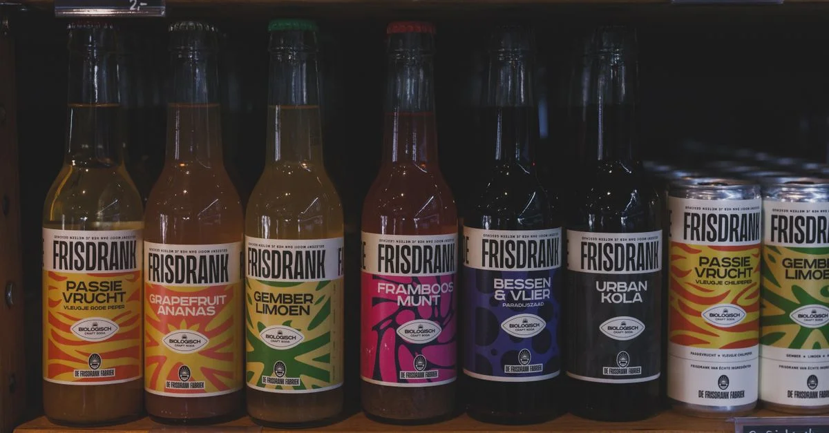 Collection dynamique de bouteilles et de canettes Frisdrank exposées sur une étagère de supermarché à Almere.