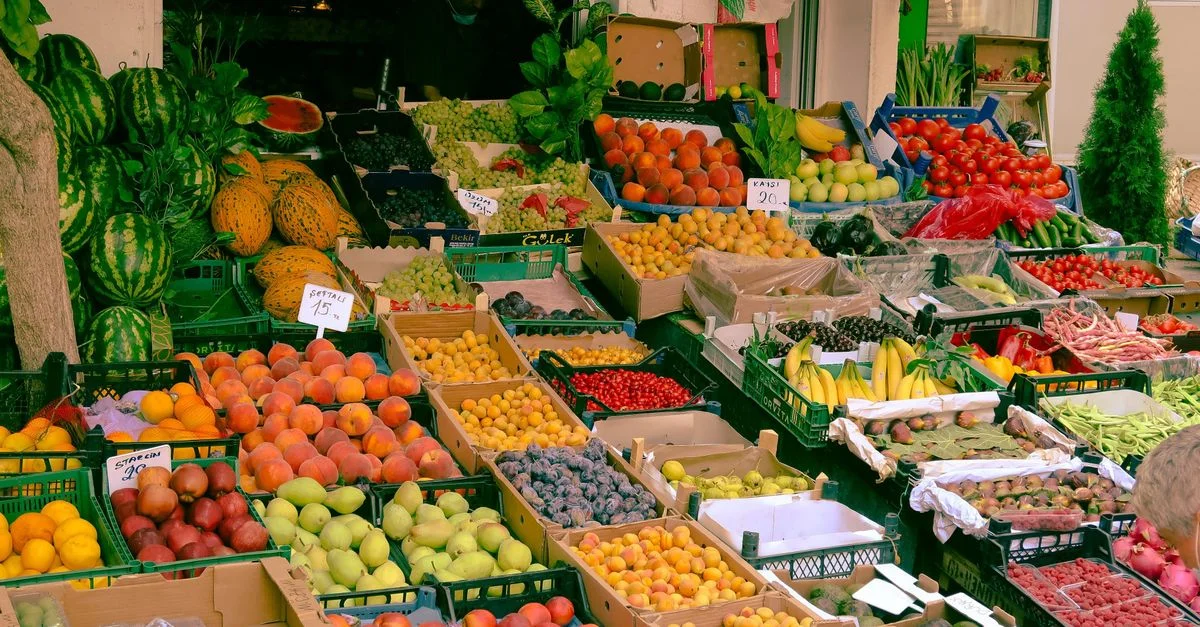 Un assortiment coloré de fruits et légumes dans un stand de marché fermier en plein air.